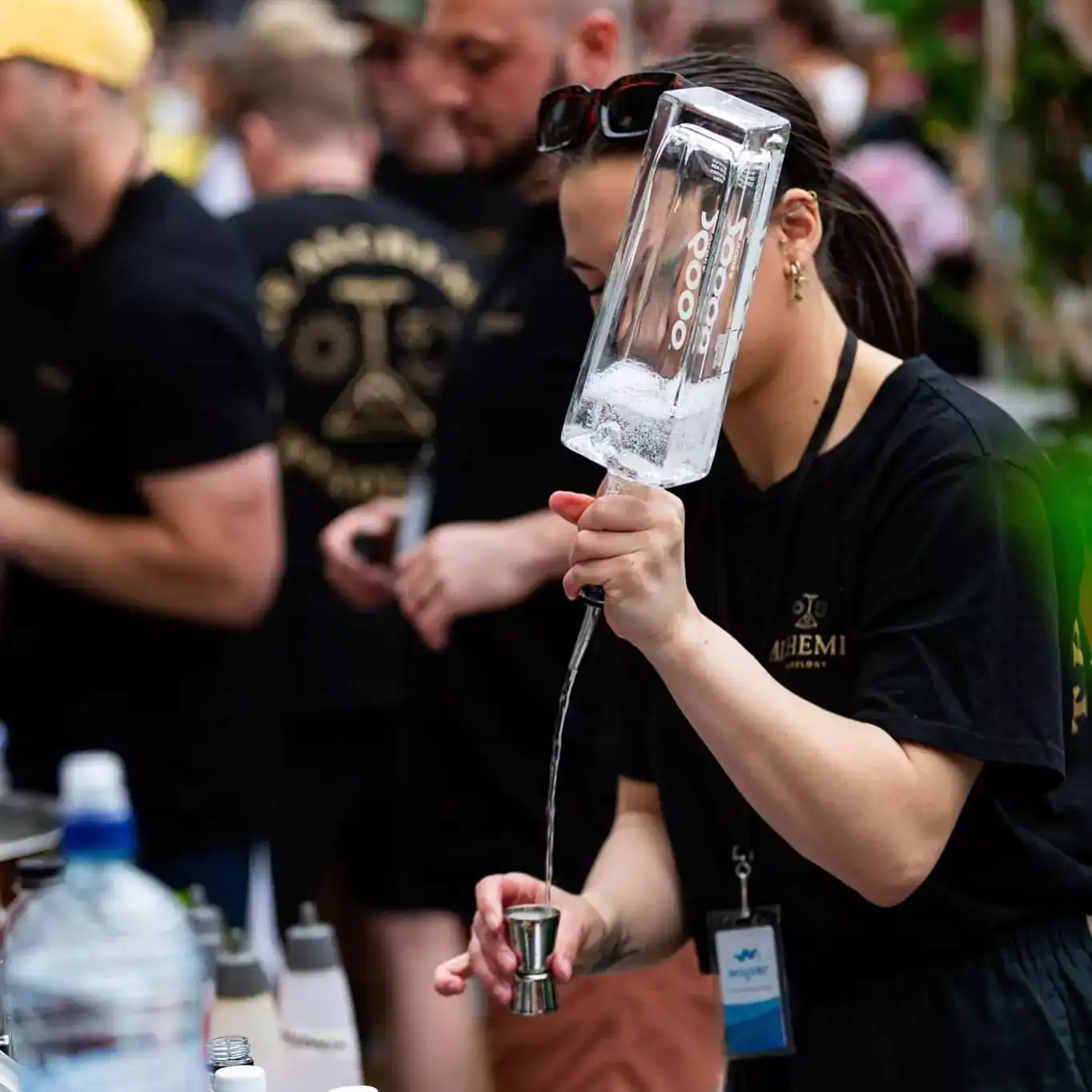 at a festival, a bartender skillfully pours a vodka from a height to prepare a cocktail